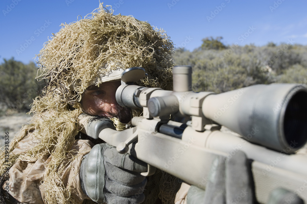 US army soldier in grass camouflage pointing rifle US army soldier in grass camouflage pointing rifle