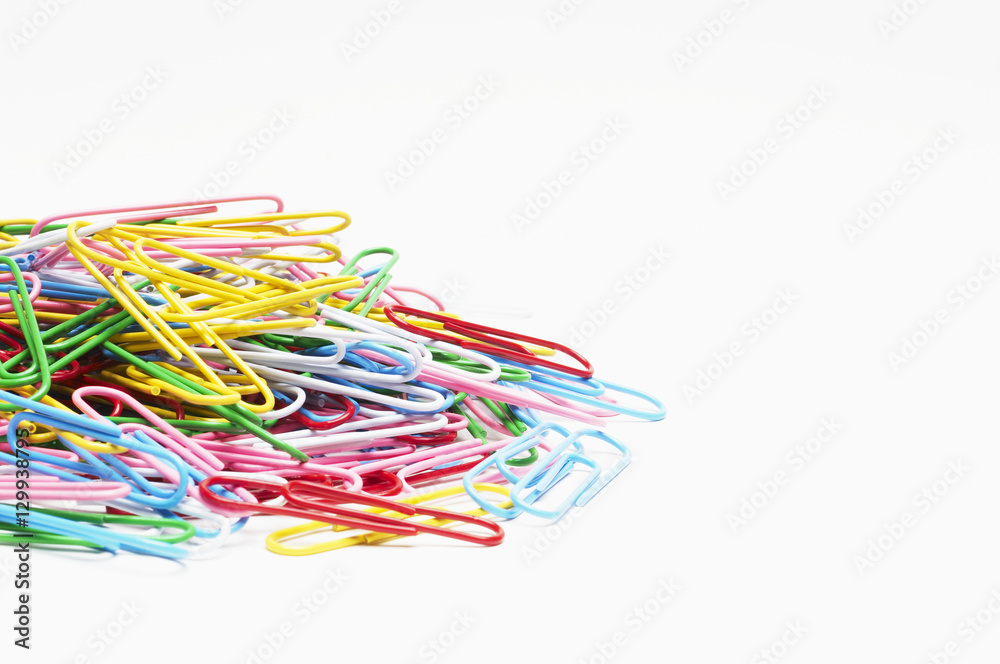 Heap of multicolored paperclips over white background