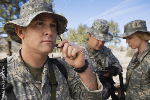 Male soldier holding microphone with colleagues in field