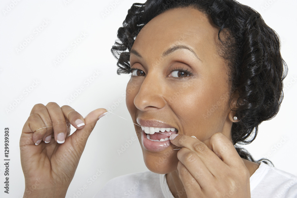 Φωτογραφία Closeup portrait of an African American woman flossing her teeth on white backgr