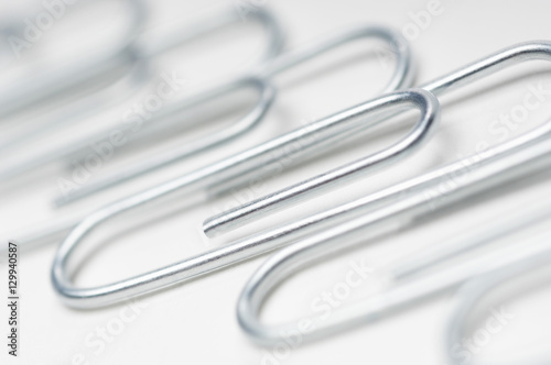 Detail of steel paperclips in a row over white background