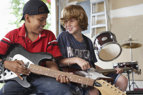Valokuva Happy multiethnic boys playing guitars in garage
