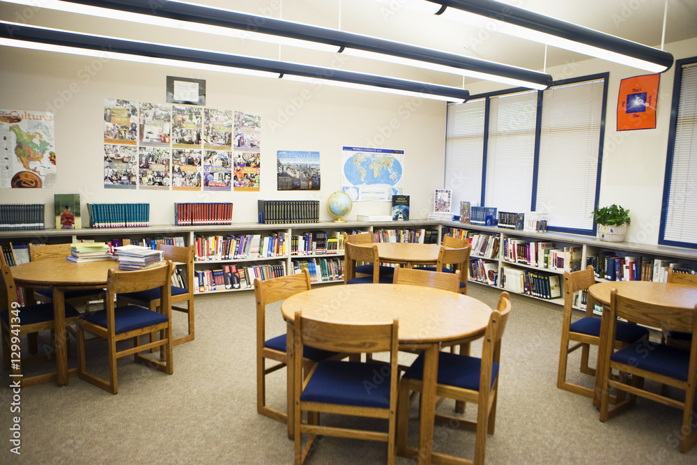 Tables and chairs with book shelves arranged in high school library