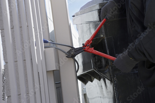 Closeup of a thief's hands cutting wire with cutter to open the gate photo