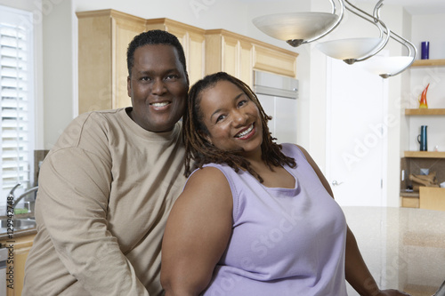 Portrait of an obese African American couple standing together in kitchen