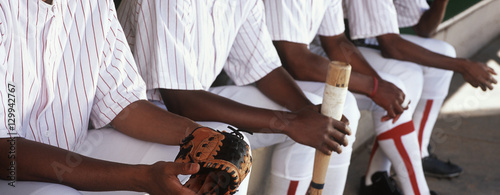 Midsection of baseball players sitting together in dugout