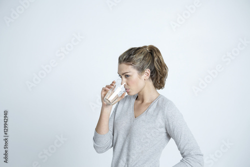 Beautiful young woman drinking water from glass isolated over colored background