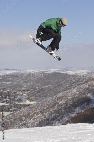 Full length of male snowboarder performing stunts on snowy hill