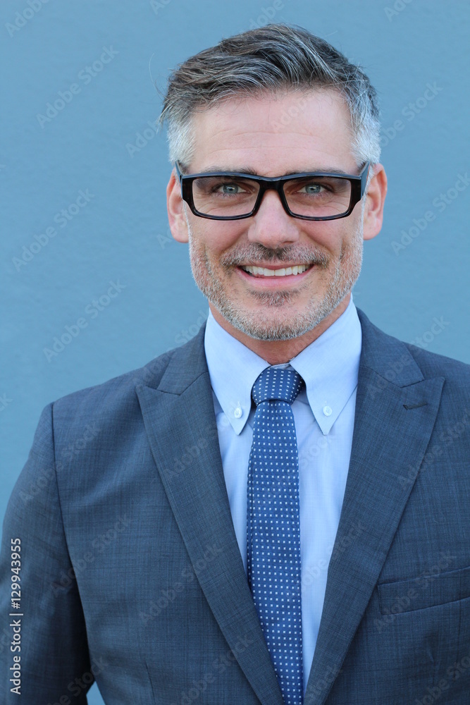 Close up Middle Age Man Wearing Business Suit and Eyeglasses Smiling at the Camera, Isolated on Blue Background.