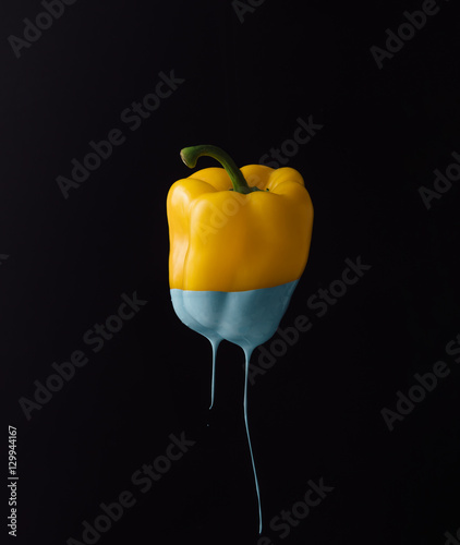 Obraz na płótnie Żółta papryka z kapiącą niebieską farbą na ciemnym tle
