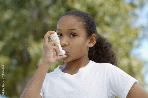 Closeup of a girl using asthma inhaler photo
