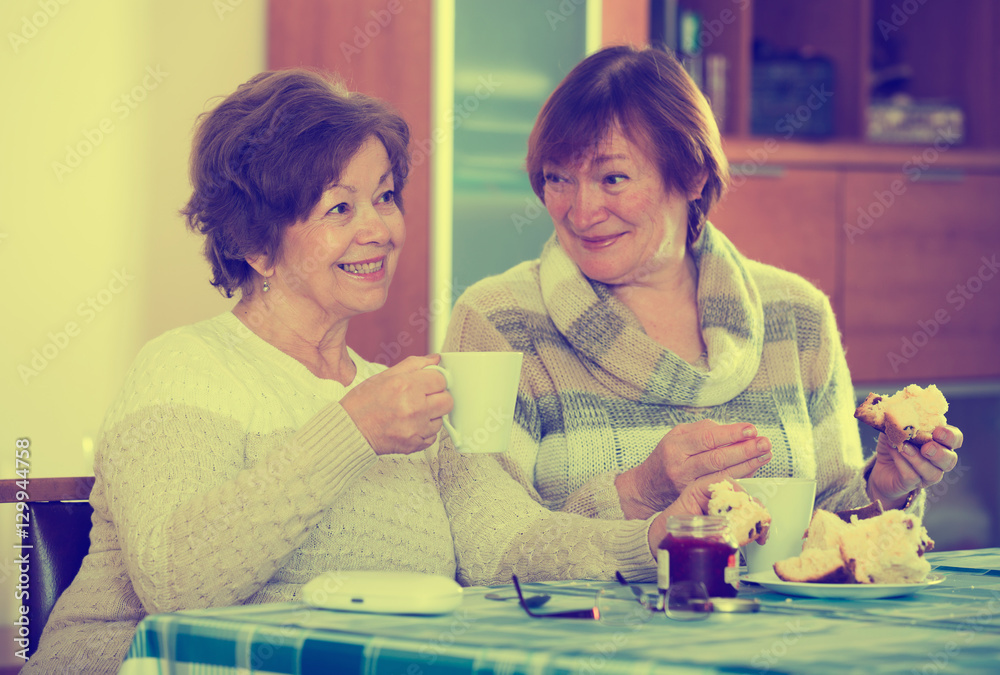 Fototapeta premium Mature women watching movie and drinking tea indoor