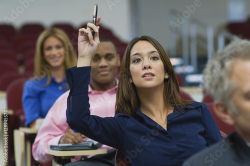 Fotografia Female executive raising hand during a business lecture amid colleagues
