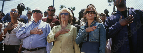 Multiethnic group of people standing together for national anthem photo