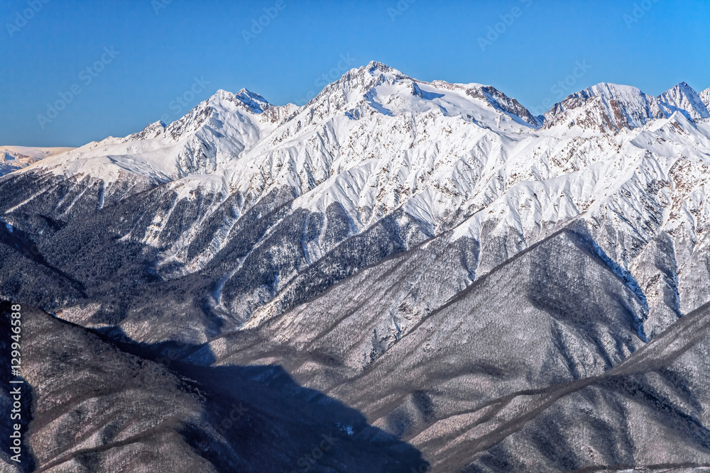 Beautiful snowy mountain peaks and blue sky scenic winter landscape of the Main Caucasus ridge on a sunny day