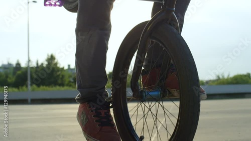 SLOW MOTION CLOSE UP: Extreme bmx biker riding manual trick at sunset photo