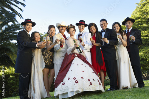 Portrait of a beautiful Quinceanera standing with family and friends in lawn
