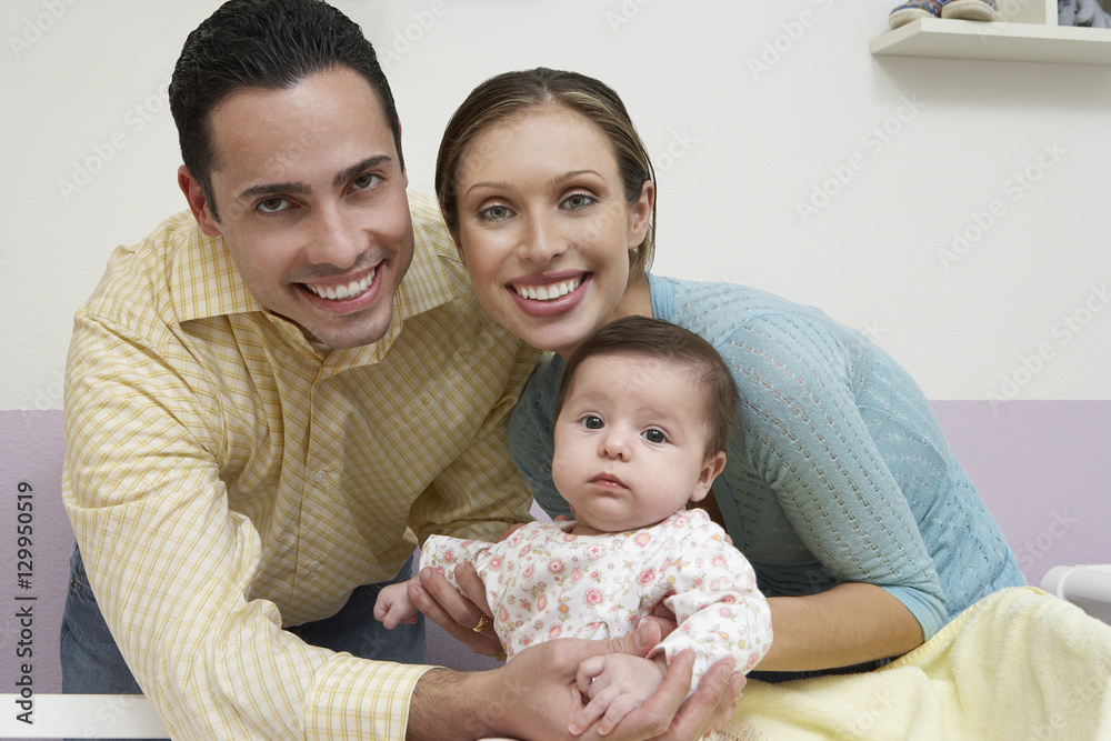 Portrait of a multiethnic happy couple smiling with baby at home Portrait of a multiethnic happy couple smiling with baby at home