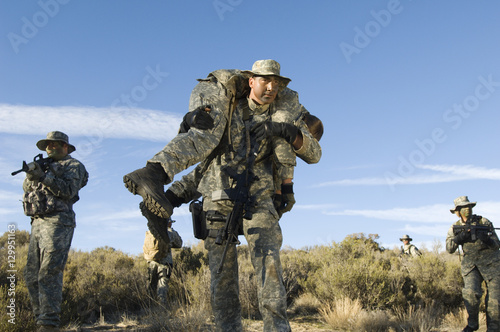 Принти на полотні US military man carrying injured female solider on shoulder with teammates in th