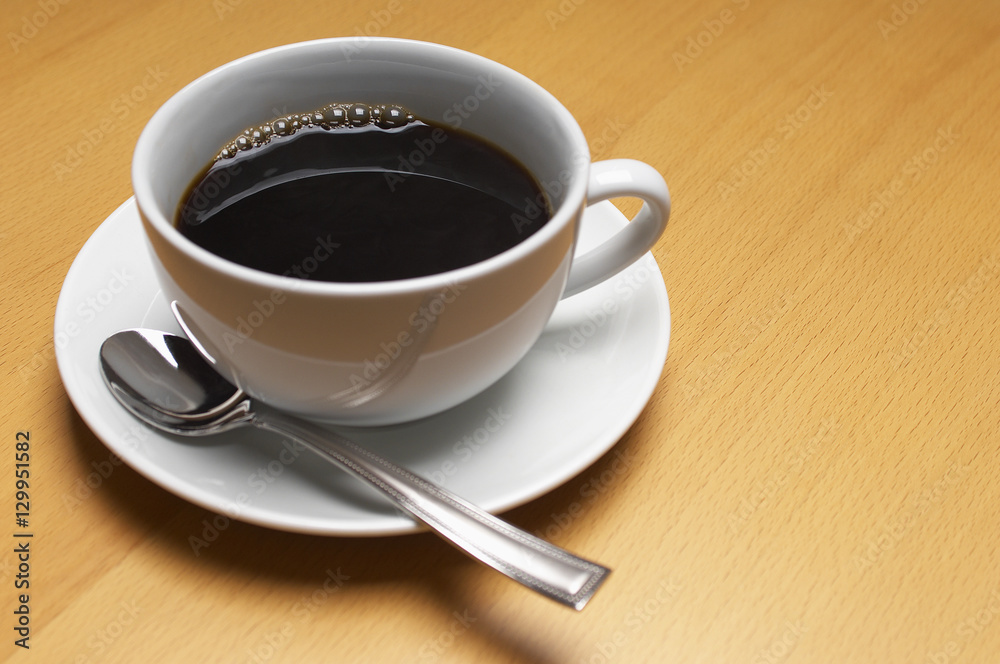 Isolated coffee cup with spoon in saucer on wooden surface Isolated coffee cup with spoon in saucer on wooden surface