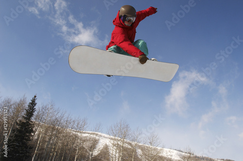 Low angle view of young male snowboarder jumping against sky
