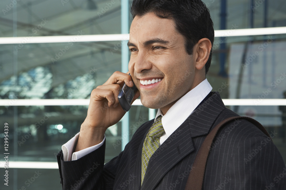 Happy businessman using cell phone outside office