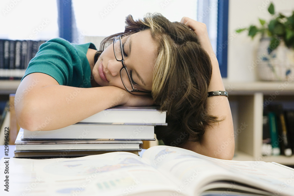Beautiful female high school student sleeping on stack of books in ...