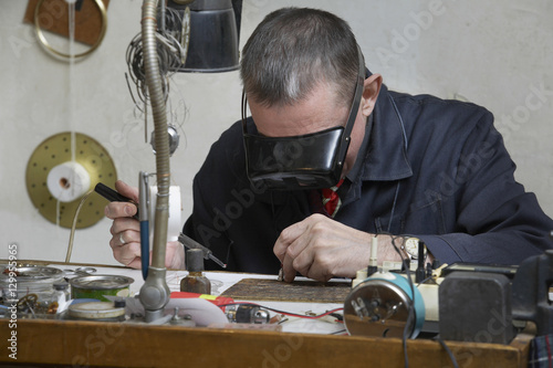 Φωτογραφία Middle aged repairman working on an old clock in workshop