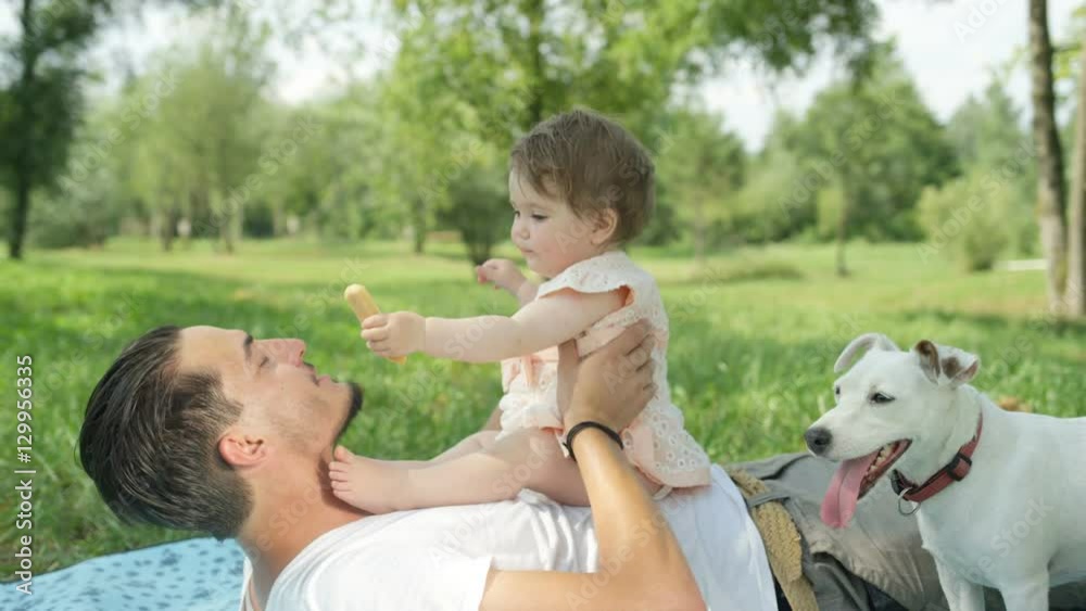 SLOW MOTION: Smiling young father playing with baby daughter in local park SLOW MOTION: Smiling young father playing with baby daughter in local park