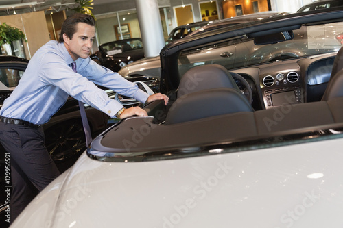 Car salesperson leaning on car