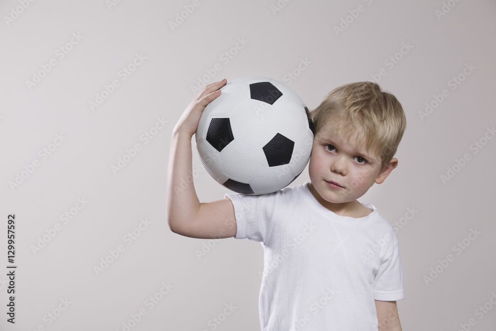 Portrait of a little boy holding soccer ball against white background