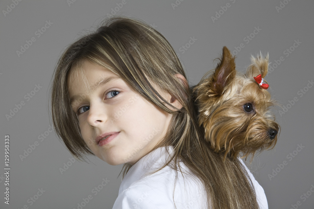 Closeup portrait of a young girl holding dog against gray background Closeup portrait of a young girl holding dog against gray background