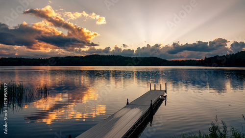 Slika na platnu A dock jutts out into a lake at sunset on a northern Wisconsin lake