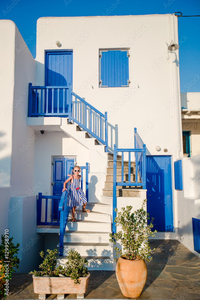 Typical house with blue balconies, stairs and flowers. Little girl on ...