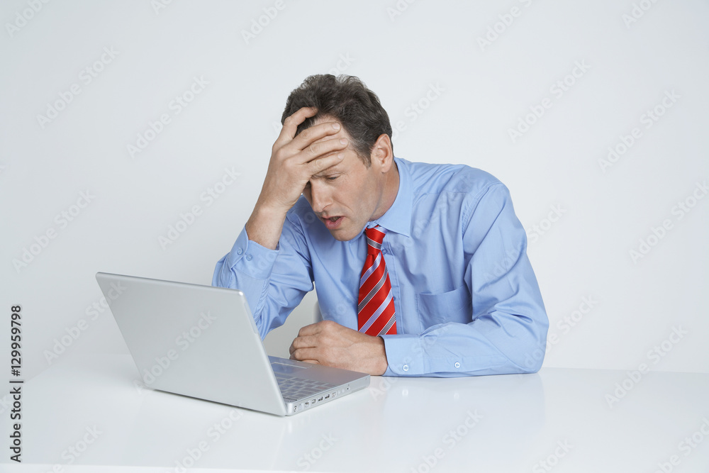 Businessman with hand on head looking at laptop isolated over white background Businessman with hand on head looking at laptop isolated over white background