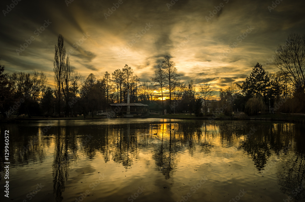 Spectacular sunset with clouds in the sky. Beautiful sunset over a lake in the city park.