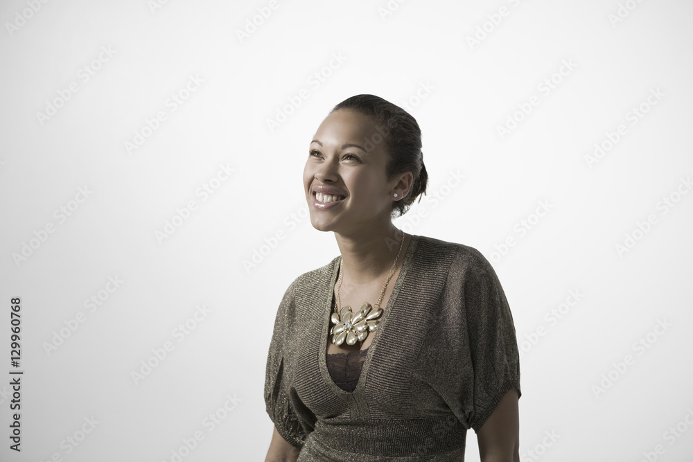 Smiling young woman looking up against gray background Smiling young woman looking up against gray background