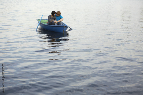 Loving young couple cuddling in rowboat at lake