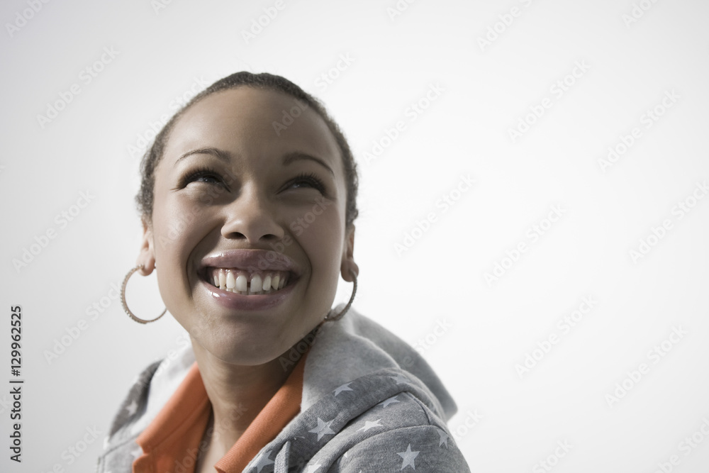 Smiling young woman looking up against gray background Smiling young woman looking up against gray background