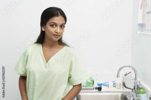 Portrait of an Indian female nurse standing by disinfection sink at clinic