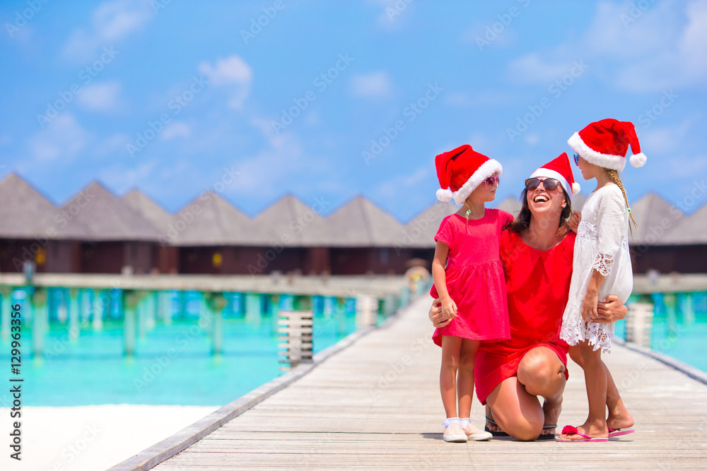 Obraz premium Young mother and little girls in Santa hat on Christmas holidays