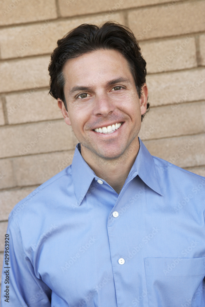 Portrait of a happy man standing against brick wall Portrait of a happy man standing against brick wall