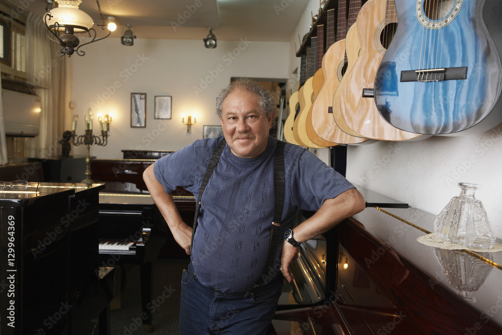 Portrait of middle aged male owner leaning in music store Portrait of middle aged male owner leaning in music store