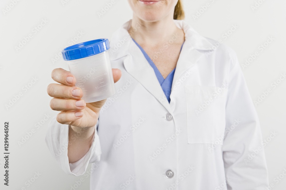 Midsection of a female nurse holding empty sample bottle isolated over white background Midsection of a female nurse holding empty sample bottle isolated over white background