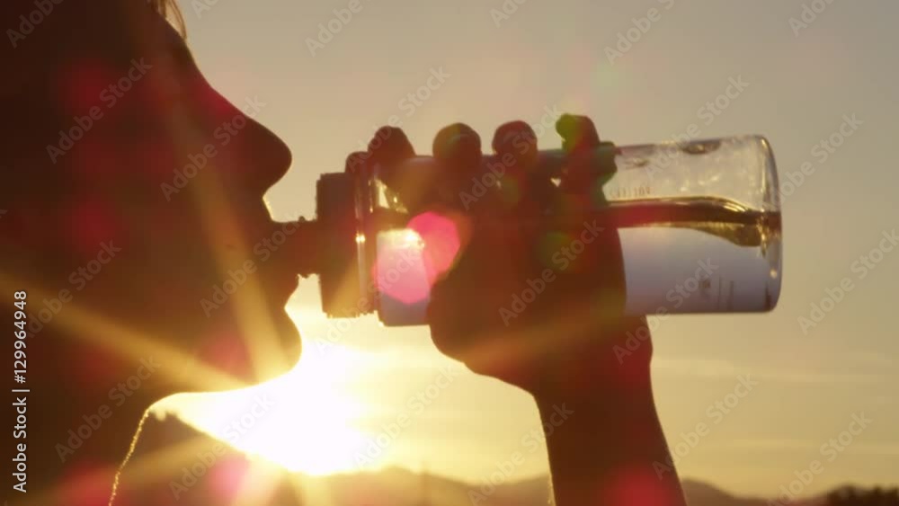 Close up portrait of cute young woman drinking fresh water from plastic bottle