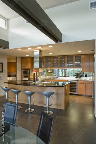 View of a spacious kitchen with stools at the island in modern house