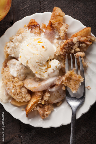 Top view of large dish of apple crisp with vanilla ice cream on top