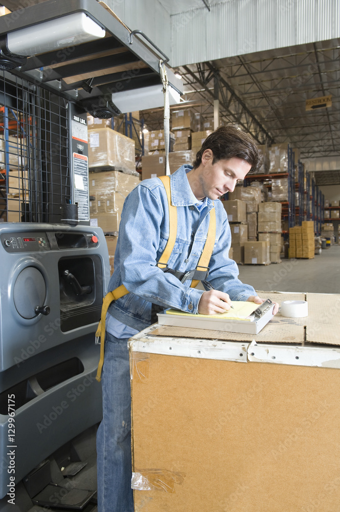 Side view of a man making notes in distribution warehouse Side view of a man making notes in distribution warehouse