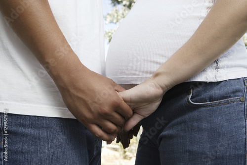 Midsection of an expectant couple holding hands