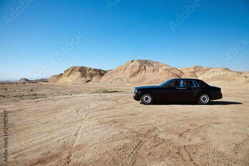Luxury car parked on unpaved road near mountains